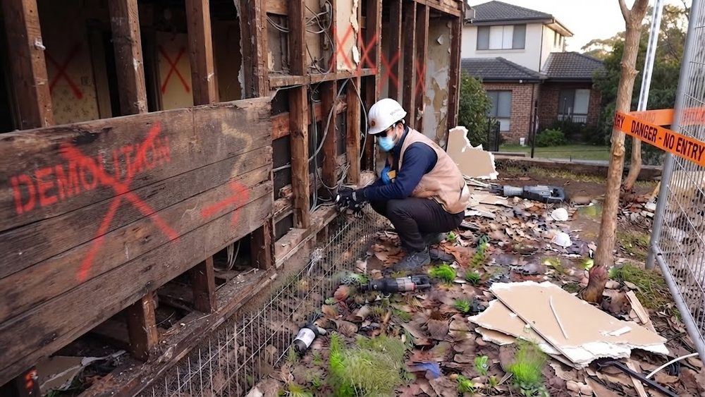 Vivienda marcada para demolición con técnico de Groupest trabajando en el cierre perimetral antes de la faena