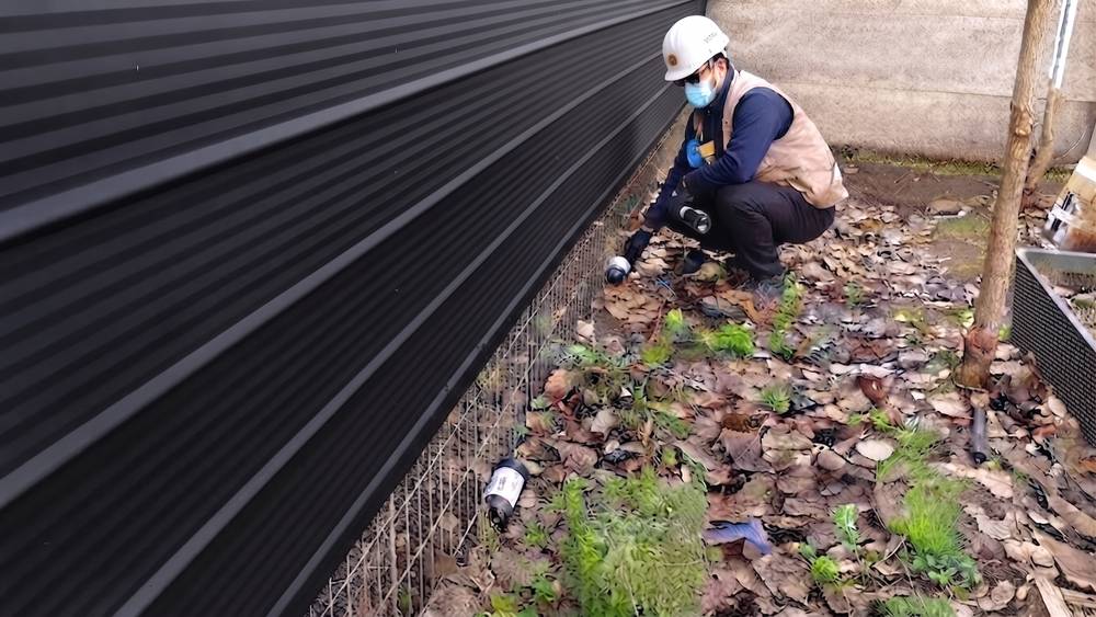 Inspección técnica del perímetro exterior de una instalación por técnico de Groupest, con casco, mascarilla y linterna de revisión