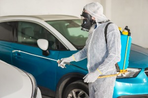 Técnico de Groupest sanitizando un vehículo con equipo de aspersión y protección completa